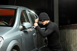 Thief with a robbery mask trying to steal an autobmobile