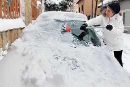 Woman cleaning snow from the car