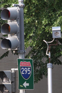A camera is placed near a traffic light for drivers who run red lights on Constitution Avenue in Washington, DC. The camera will take a picture of the car and license plate and the offender will be mailed a citation.