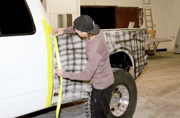 The final coat shot after the gray primer was a black stripped guidecoat layer. Once the primer cured, the truck came back out of the paint booth and was taped off for final sanding. It was block and wet-sanded to get a smooth, flat base for the paint to follow.