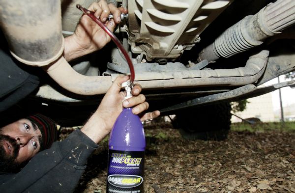 After cleaning the drain plug magnet off again, a thin covering of light shavings is perfectly normal—reinstall it and wipe everything down. You can then start refilling your transmission with the Mopar MS-9224 transmission fluid or equivalent. An approved equivalent fluid will say “Meets MS-9224,” usually found on the back of the bottle. You will need a 14mm hex key for the fill plug, located midway up on the passenger side of the transmission.