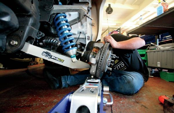 Being heavy, a floor jack is used to lift the knuckle/hub assembly in place. Note that the axle is fed through the hub assembly at the same time, so this step may require a helping hand.